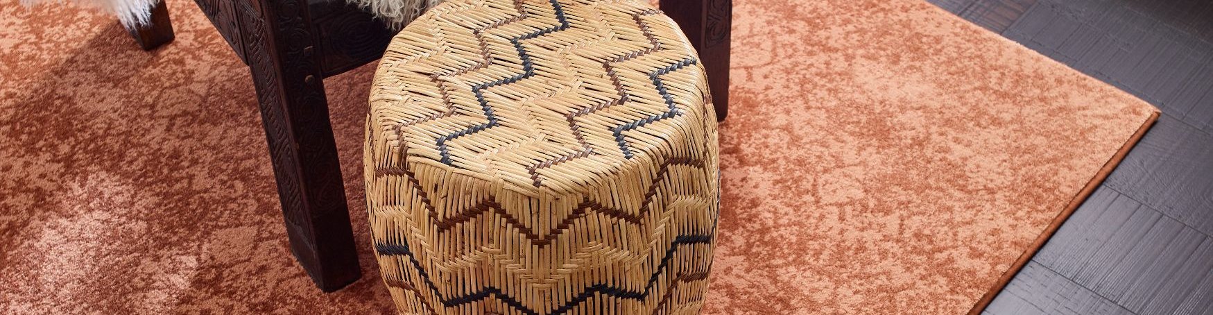 black coffee table and patterned small chair on orange rug from Carter Carpets & Vinyl in Temperance, MI